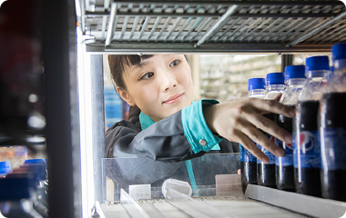 冷蔵棚にペットボトル飲料を補充するスタッフ