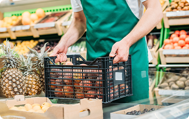 青果売場で果物の入ったカゴを持つスタッフ